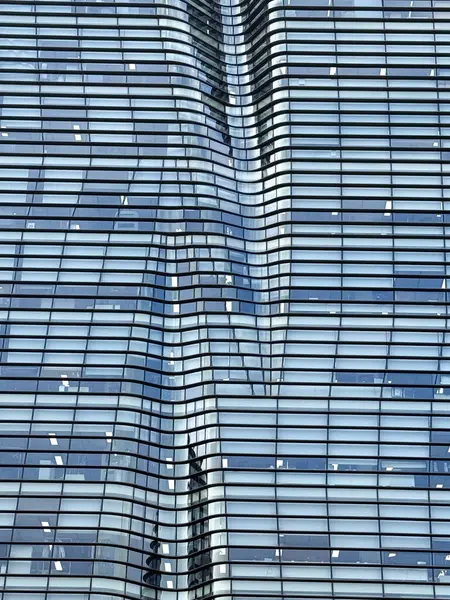 Açık ve kapalı pencereli bir cam bina cephesi organik şekiller yaratıyor..