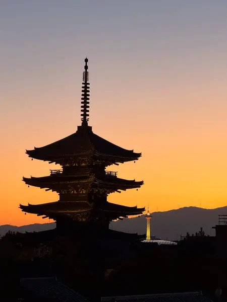 Japonya 'da parlayan turuncu bir günbatımına karşı karanlık bir tapınak silueti..