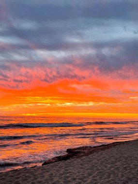 Pasifik Okyanusu boyunca Meksika 'da bir plajda inanılmaz turuncu gün batımı. Renkli gökyüzü ve sakin bir kıyı şeridi var..