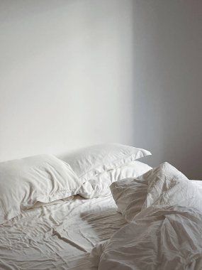 Minimalist beyaz yatak odası, geniş yatak odası ve yumuşak sabah ışığı..