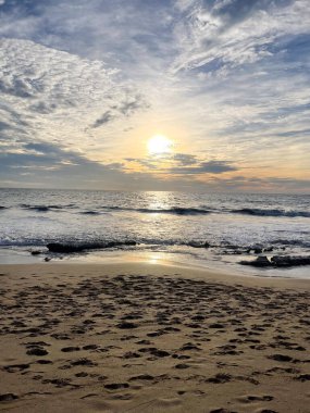 Okyanus dalgaları, turuncu bir günbatımı gökyüzünün altında, Mazatlan sahilinde bulutlarla..