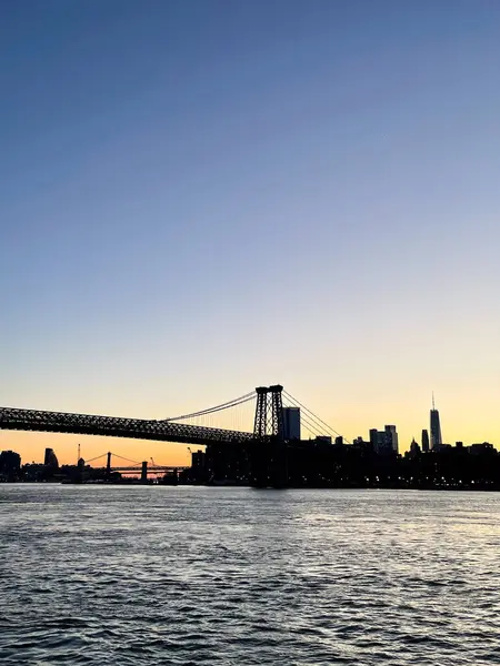 Manhattan Köprüsü ve Williamsburg 'dan görünen ufuk çizgisi ile Doğu Nehri üzerinde gün batımı.