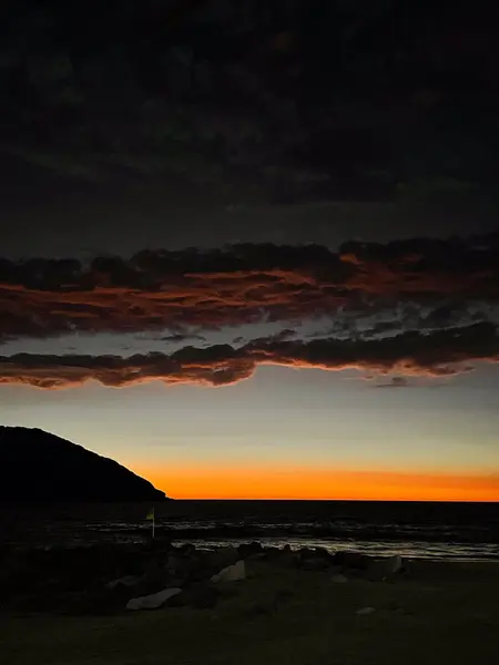 Karanlık okyanus dalgalarıyla gün batımı ve Mazatlan, Meksika 'da arka planda bir ada..