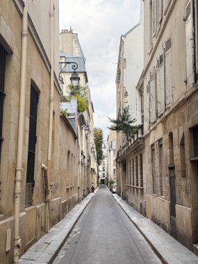 Empty narrow alley in Saint Germain, Paris with stone walls and old European architecture.