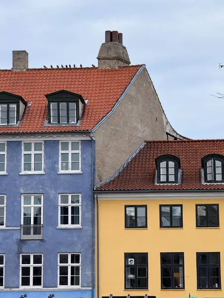 Bright blue and yellow traditional houses with red roofs and white framed windows in Copenhagen, Denmark.