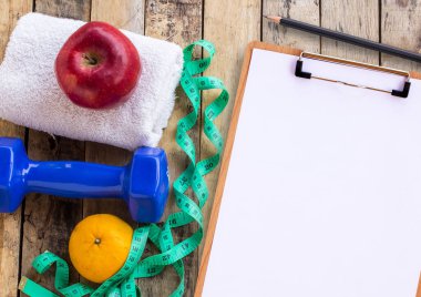 Mavi halter, beyaz havlu, ölçme bant ve ahşap masa üzerinde kırmızı elma ile tıbbi formu. Fitness kavramı