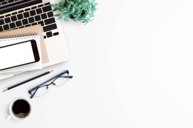 Laptop bilgisayarı, akıllı telefonu, boş ekranlı bardakları ve bir fincan kahvesi olan modern beyaz ofis masası. Herhangi bir tasarım için fotokopi alanı olan üst görünüm. İş yeri ofis tablosu kavramı