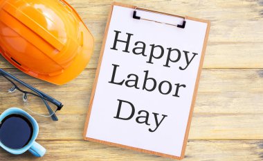 Turuncu kasklı, gözlüklü, panolu ve eski ahşap masa arkaplanlı bir fincan kahve. Kullanım alanı ve herhangi bir tasarım için. İş ve işçi günü kavramı.