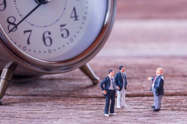 Minyatür insanlar: işadamı rakamlar bulanık çalar saat arka plan ile zemin ve iş görüşmeleri üzerinde duran. para ve mali kavramı. kopya alanı iş arka plan olarak kullanmak için