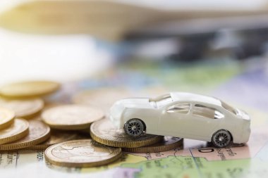 Modern model beyaz oyuncak araba park yığın altın sikkeler üzerinde kapatın. Tasarruf, mali ve taksit ödeme kavramı. ve bulanık uçak arka plan.