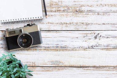 Vintage fotoğraf makinesi, defter, kalem ve taze çiçek ile ofis Resepsiyon ahşap masaları. Üstten Görünüm kopya alanı ile. Üst eski fotoğraf makinesi Beyaz ahşap masa üzerinde görüntüleyin. Retro vintage filtre.