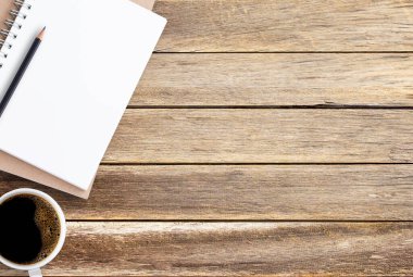 Boş kağıt defter, kalem ve kahve kahverengi ahşap masa arka plan üzerinde. Üstten görünüm kopya alanı (seçici odak) ile. Ofis resepsiyon tablosu konseptiyle kopya alanı herhangi bir tasarım için.