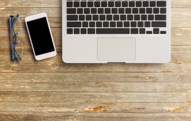 Dizüstü bilgisayar, gözlük ve ahşap masa üstten görünüm kopya alanı ile akıllı telefon