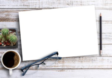 Boş kağıtlı ahşap ofis masası, bir fincan kahve, kalem ve bardak, düz yatak. Kopyalama alanı olan üst görünüm (seçici odak). Ofis masası konsepti.