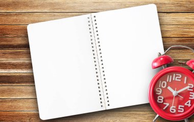 Kağıt not defteri, kırmızı alarm saati ve çalışma yerindeki ahşap masa arkaplanlı kahve fincanı. Herhangi bir tasarım için alanı kopyala.