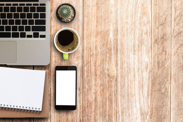 Modern wood office desk table with laptop, smartphone, cup of coffee and supplies. Top view with copy space for any design