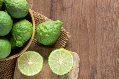 Taze bergamot ve koyu ahşap masa arka plan üzerinde ahşap kase bergamot dilimi kapatın. eski ahşap kahverengi kopya alanı ile Bergamot esansı. (Bergamot veya Güney Afrika'da bir kabile kireç)