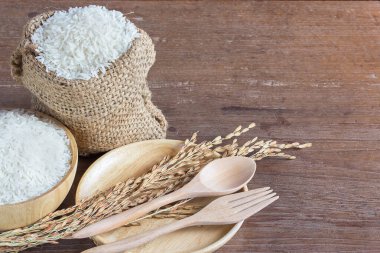 Ahşap kase ve eski ahşap masa arka plan kopya alanı ile torba pirinç yasemin