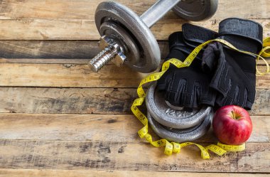 Ahşap zemin üzerinde üstten görünüm dambıl, ilave ağırlık ve siyah eldiven. Spor yaşam tarzı ve fitness kavramı.