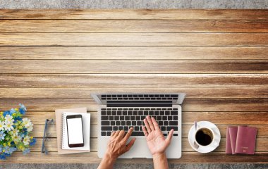 İş adamı bir fincan kahve, pasaport, gözlük ve kahverengi ahşap masaüstü çiçek ile bir dizüstü bilgisayar kullanarak eller. Üstten Görünüm kopya alanı ile. İş kavramı