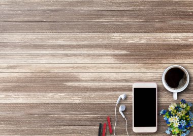 Ofis Masası ile akıllı telefon, fincan kahve ve kulaklık üzerinde kahverengi ahşap arka plan kopya alanı ile. İş kavramı.