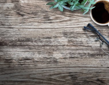 Ofisteki ahşap arka planda çiçekli, bardaklı ve kahveli ahşap masa..