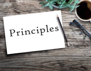 El yazısı prensipleri. Ahşap masa üzerinde boş beyaz kağıt kalem, çiçek, bardak ve iş yerindeki ahşap arka planda bir fincan kahve..