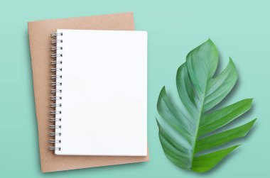 Yeşil masa arka planında yeşil izin ve defter ile üst görünüm. Herhangi bir tasarımı kopyala.