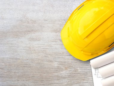 Sarı güvenlik kaskı ya da ahşap masa arkasındaki inşaat kâğıdı planları. İş kurma fikri, inşaat endüstrisi kavramı. Kullanımınız için kopyalama alanı olan üst görünüm.