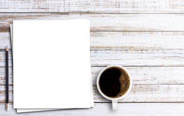 Tahta masa arkasında beyaz kağıt, kalem ve bir fincan kahve ile üst manzara