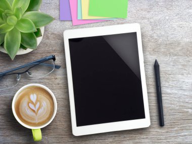 Tablet, kalem faresi, yapışkan notlar ve masa arkasında çiçek olan kahve. Kopyalama alanı olan üst görünüm. İş teknolojisi konsepti. Ev fikirlerinden bağımsız ve çalışmalı.