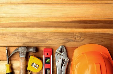 Ahşap masa arka planında inşaat aletleri. Kopyalama alanı olan üst görünüm. Çalışma günü ve iş sektörü kavramı.