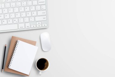 Not defterleri, klavye ve iş yerindeki beyaz masa arkasında bir fincan kahve. Tasarım için fotokopi alanı olan üst görünüm. İş ve endüstri kavramı.