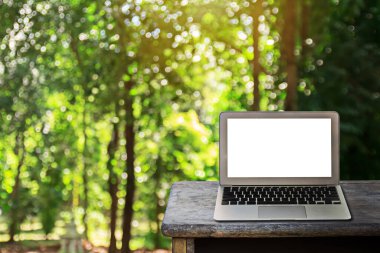 Tahta masadaki dizüstü bilgisayar, tasarım için kopyalama alanı olan bulanık yeşil bokeh arkaplan.