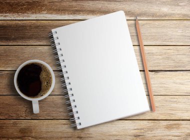 Boş defter, tahta masa arkasında kalem ve kahve. Kopyalama alanı olan üst görünüm. Ofis işyerinde sabit