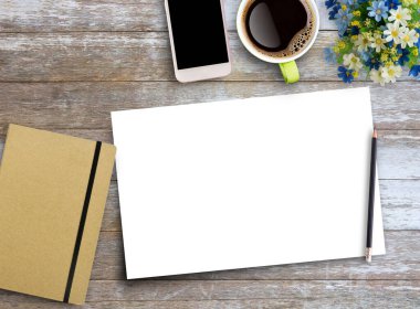 Office desk table with blank white paper,smartphone,notebook, peneil and a cup of coffee. Business and finance concept. Flat lay with blank copy space top view.