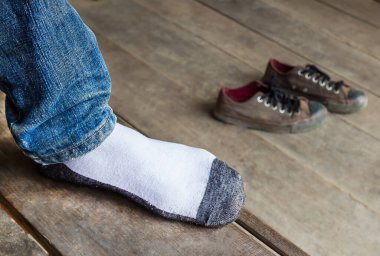Erkek çorap giyen bir ahşap zemin üzerinde bir ayak koymak ve ayakkabı arkasında yerleştirilir