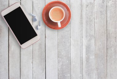 Kahve fincanı ve kulaklık üzerinde beyaz tahta arka plan ile akıllı telefon. Üstten Görünüm kopya alanı (seçici odak) ile. Ofis Resepsiyon Masa kavramı.