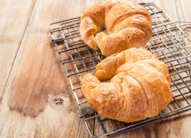 Taze kruvasanlar ızgara ve eski ahşap masa arka plan üzerinde