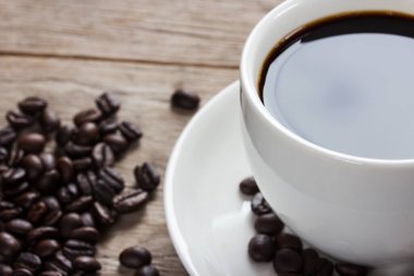 Kahve fincanı ve koyu ahşap masa üzerinde kahve çekirdekleri