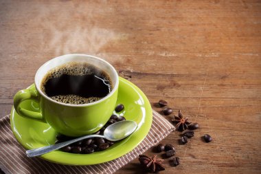 Fincan kahve ve kahve çekirdekleri kahverengi peçete ve ahşap masa