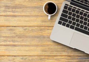 İşyerindeki kahverengi ahşap masada dizüstü bilgisayar ve kahve. Tasarımınız için kopyalama alanı olan en üst görünüm.