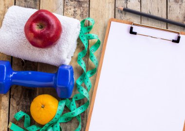 Mavi halter, beyaz havlu, ölçme bant ve ahşap masa üzerinde kırmızı elma ile tıbbi formu. Fitness kavramı