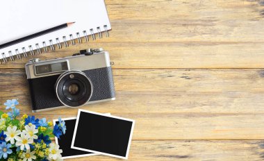 Boş defter ve vintage fotoğraf makinesi ile ahşap tablo veya ofis Resepsiyon arka plan üzerinde iki boş fotoğraf çerçeveleri üstten görünüm görüntüsü. alan tasarımı için