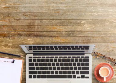 Kahverengi ahşap ofis masasının masa üstü manzaralı kahve, bardak, kalem ve not defteri. Çalışma odası. Ofis eşyaları masanın üstünde. ofis işi ve iş konsepti