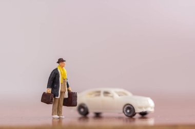 Minyatür insanlar - işadamı çanta ayakta beyaz araba bulanık arka plan ile katta devam. İş ve seyahat kavramı.