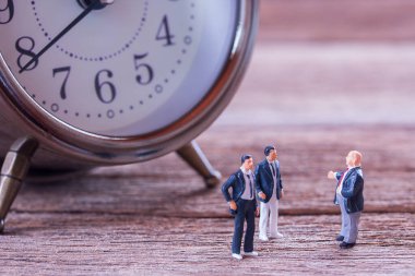 Minyatür insanlar: işadamı rakamlar bulanık çalar saat arka plan ile zemin ve iş görüşmeleri üzerinde duran. para ve mali kavramı. kopya alanı iş arka plan olarak kullanmak için