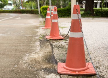 Asfalt üzerinde üst üste duran parlak turuncu trafik konileri kapatın. sarı kırmızı ve beyaz trafik işaretleri ile beton kaldırım.