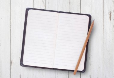Beyaz ahşap masa arka plan üzerinde Üstten Görünüm boş beyaz kapak defter kalem ile. İş ve eğitim kavramı.