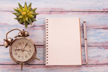 Düz yatıyordu fotoğraf boş defter, kalem ve ahşap masa arka plan üzerinde çiçek ile çalar saat ile. Kopya alanı tasarım ile Üstten Görünüm